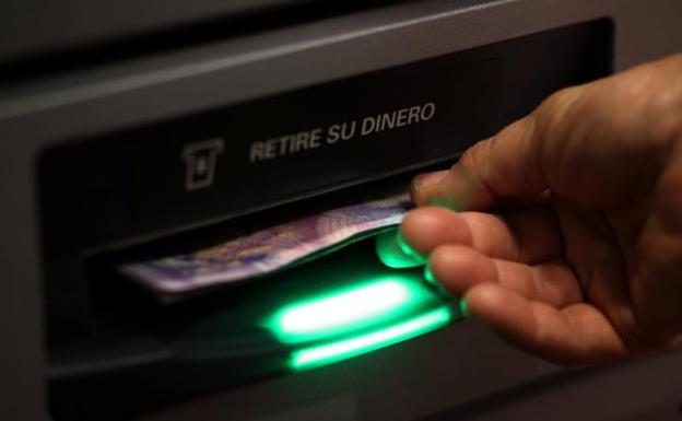 Una persona retira dinero de un cajero.