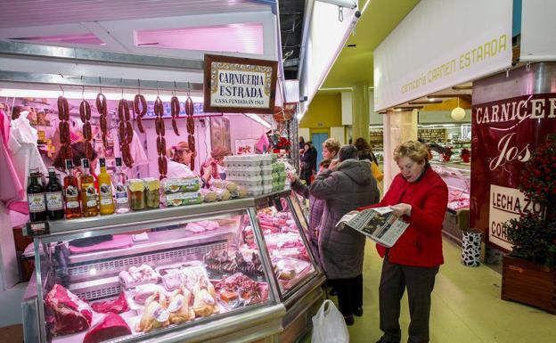 Varias personas compran alimentos frescos en la remodelada Plaza de Abastos que ya luce su nueva imagen./Luis Palomeque