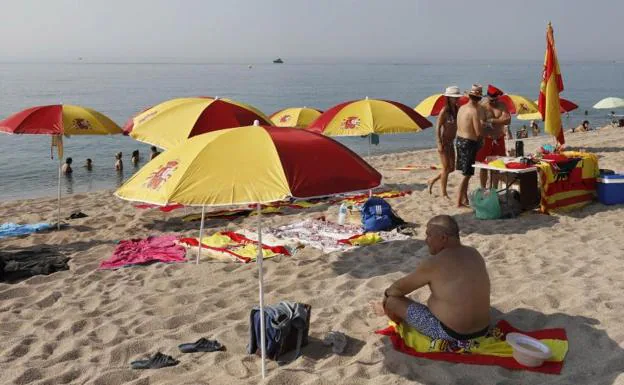 Plantan doce sombrillas con los colores de la bandera de España en la playa de Arenys de Mar